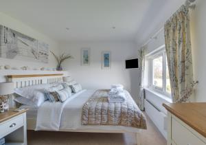 a white bedroom with a bed and a window at Finn Cottage in Bamburgh
