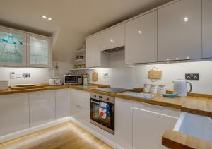 a kitchen with white cabinets and a stove top oven at Finn Cottage in Bamburgh