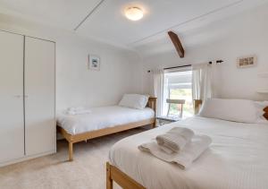 a white bedroom with two beds and a window at Castle Point Cottage Craster in Craster