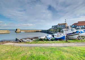 a group of boats sitting on the grass near the water at Castle Point Cottage Craster in Craster