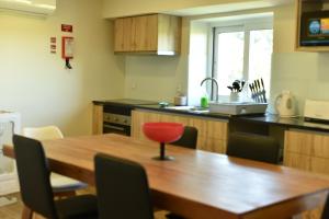 uma cozinha com uma mesa de madeira e uma cadeira vermelha em CASA DA `VÓ MICAS em Cardeal