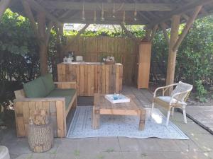a wooden pergola with a table and a bench at Garden studio in Rijsbergen