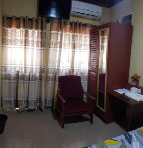 a bedroom with a chair and a desk and a mirror at Appart'hotel britannia in Yaoundé