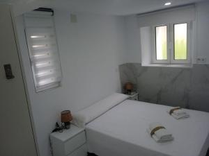 1 dormitorio blanco con 1 cama y 2 ventanas en Bajo cerca de la playa de Peligros, en Santander