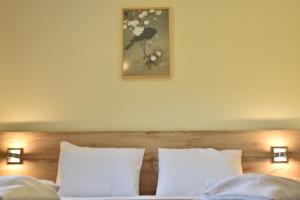 uma cama com almofadas brancas e uma fotografia na parede em CASA DA `VÓ MICAS em Cardeal