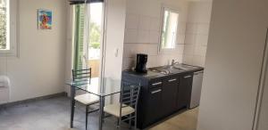 een keuken met een glazen tafel en een wastafel bij Studio dans résidence avec piscine in Calvi