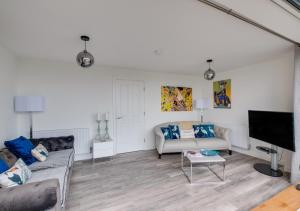 a living room with two couches and a flat screen tv at Coastal Retreat in Amble