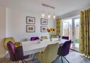 a dining room with a white table and purple chairs at Coastal Retreat in Amble