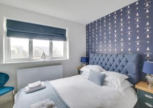 a bedroom with a large bed with a blue headboard at Coastal Retreat in Amble