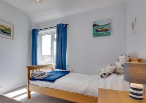 um quarto com uma cama com cortinas azuis e uma janela em Porthole Cottage em Beadnell