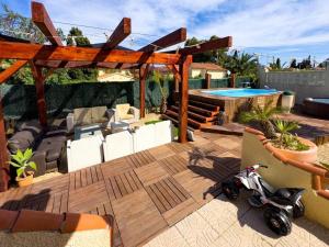 a deck with a swimming pool and a scooter parked on it at Calpe chalet privado piscina a 5min de la playa y centro jacuzzi barbacoa wifi aire in Calpe