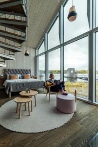 een man in een stoel in een kamer met grote ramen bij Arctic Bath in Harads