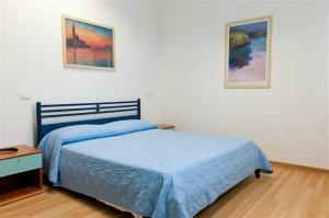 1 dormitorio con 1 cama azul y 2 cuadros en la pared en MiMa Hostel Moorea, en Milano Marittima