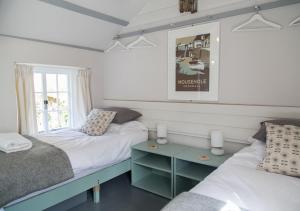 a bedroom with two beds and a table and a window at Molly Muppet in Mousehole