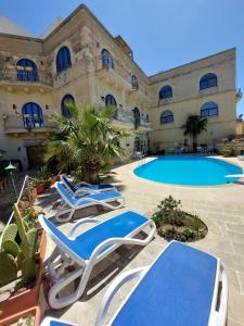 a resort with lounge chairs and a swimming pool at Villa Serenity B&B in Sannat