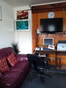 a living room with a couch and a desk with a tv at Mablet Family Home Stay in Auckland