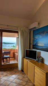 a living room with a television and a view of the ocean at Porto Coda Cavallo - Salina Bamba in San Teodoro