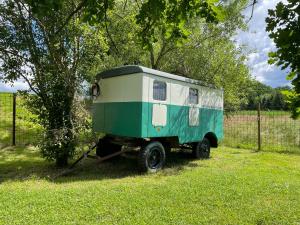 a green and white trailer parked next to a tree at Residence Safari Resort - Magic Bus in Borovany
