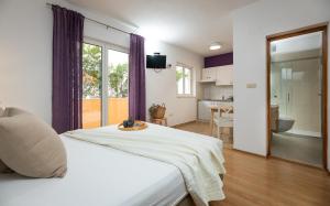 a bedroom with a white bed and a kitchen at Apartments Sunny Elza in Hvar