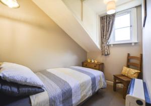 a bedroom with a bed and a window at Larch Cottage in Craster