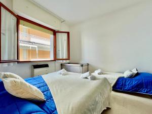 two beds in a room with a window at Relax a 800 mt dal Mare - Free Parking, A/C e WiFi in Pietra Ligure