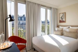 um quarto de hotel com uma cama e uma grande janela em Alberte Hôtel em Paris