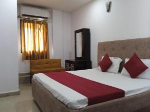 Hotel Metro Regency في لاكناو: غرفة نوم بسرير كبير ومخدات حمراء