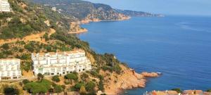 a large building on a cliff next to the water at Espiga, Cala privada Tossa de Mar in Girona