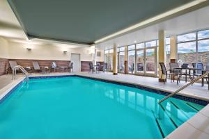- une piscine avec des chaises et des tables dans une chambre d'hôtel dans l'établissement Fairfield Inn & Suites by Marriott Livingston Yellowstone, à Livingston