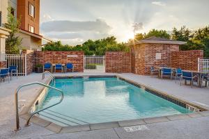 une piscine avec des chaises bleues et un mur en briques dans l'établissement TownePlace Suites by Marriott Fayetteville N / Springdale, à Johnson