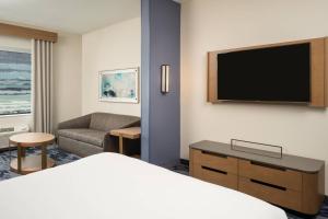 ein Hotelzimmer mit einem Bett und einem Flachbild-TV in der Unterkunft Fairfield Inn & Suites Vero Beach in Vero Beach