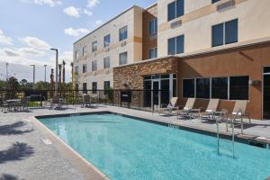 einem Pool vor einem Hotel mit Stühlen und einem Gebäude in der Unterkunft Fairfield Inn & Suites Vero Beach in Vero Beach