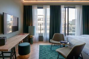 a hotel room with a bed and a desk and chairs at Gekko House Frankfurt, a Tribute Portfolio Hotel in Frankfurt