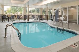 Fairfield Inn & Suites by Marriott Wenatchee في ويناتشي: حمام سباحة في الفندق مع الكراسي والطاولات