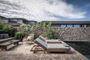 Domes Zeen Chania, a Luxury Collection Resort, Crete في كاتو داراتسو: فناء مع أريكة وكراسي وجدار حجري