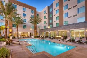 a hotel pool with chairs and palm trees in front of a building at TownePlace Suites by Marriott Los Angeles LAX/Hawthorne in Hawthorne