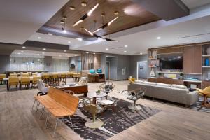 a hotel lobby with a waiting area and tables and chairs at TownePlace Suites by Marriott Los Angeles LAX/Hawthorne in Hawthorne