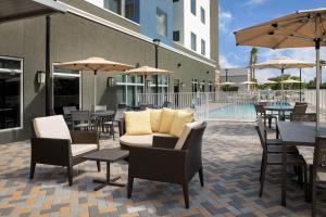 un patio al aire libre con mesas, sillas y sombrillas en Residence Inn Doral Mall Area, en Doral