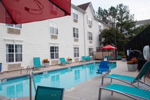a swimming pool with blue chairs and a building at TownePlace Suites by Marriott Atlanta Alpharetta in Alpharetta