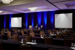 una sala conferenze con tavoli e sedie e due schermi di Milwaukee Marriott West a Waukesha