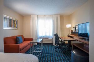 a hotel room with a couch and a desk and a television at Fairfield Inn & Suites Dallas Lewisville in Lewisville
