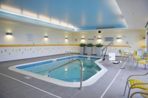 a large swimming pool in a room with tables and chairs at Fairfield Inn and Suites Canton South in Canton