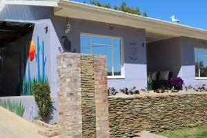 a house with a stone pillar in front of it at Sunset Cottage - Cheerful 1 Bedroom Cottage in Barrydale