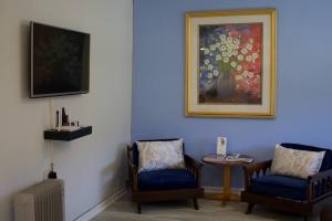 a room with two chairs and a painting on the wall at Sunset Cottage - Cheerful 1 Bedroom Cottage in Barrydale