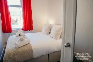 um quarto com uma cama com cortinas vermelhas e uma janela em Ainslie St by Prestige Properties SA em Barrow in Furness
