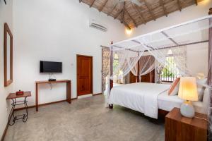 a bedroom with a white bed and a television at Halcyon Galle in Galle