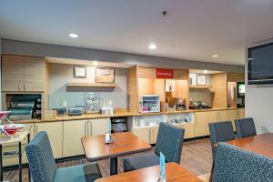 a kitchen with wooden cabinets and tables and chairs at TownePlace Suites Cleveland Streetsboro in Streetsboro