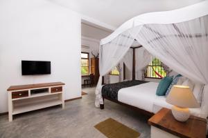 a bedroom with a canopy bed and a television at Halcyon Galle in Galle