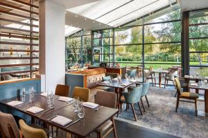 a restaurant with tables and chairs and large windows at Delta Hotels by Marriott Cheltenham Chase in Cheltenham