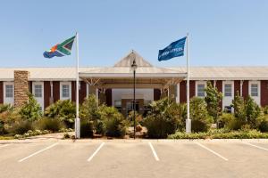 a hotel with two flags in a parking lot at Protea Hotel by Marriott Bloemfontein in Bloemfontein